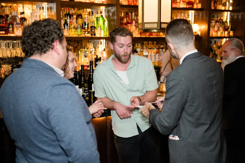 Guests reacting to a close-up card effect performed at a bar during a private event