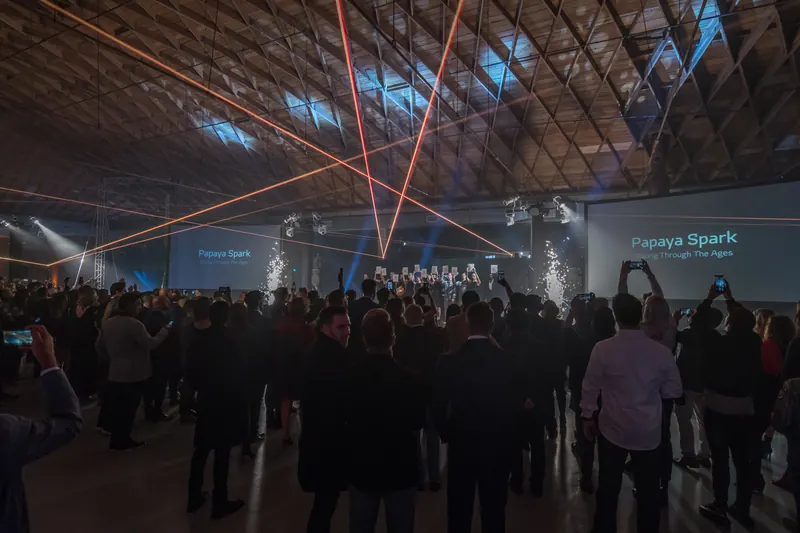 Large corporate product launch event with stage lighting and a standing audience