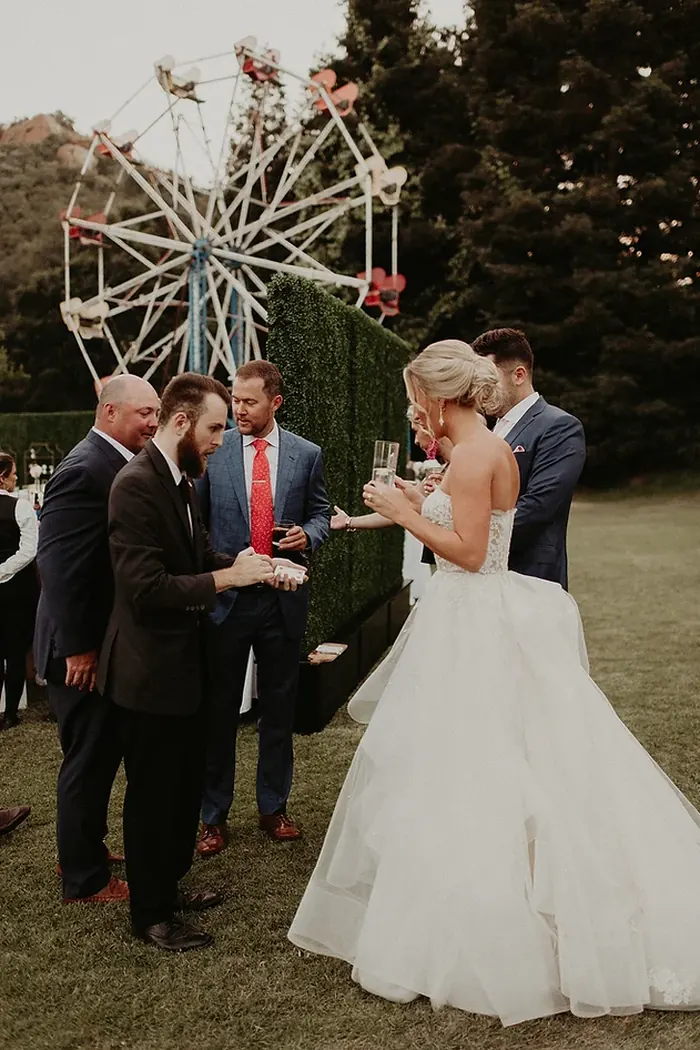Close-up magician performing for a bride and guests during an outdoor wedding cocktail hour