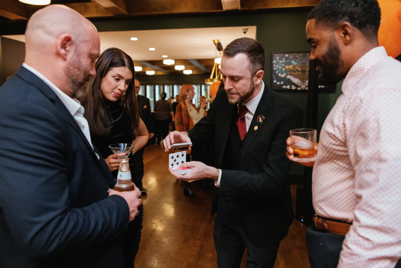 Guests watching Frankie Foti perform card magic during a Nashville corporate cocktail hour