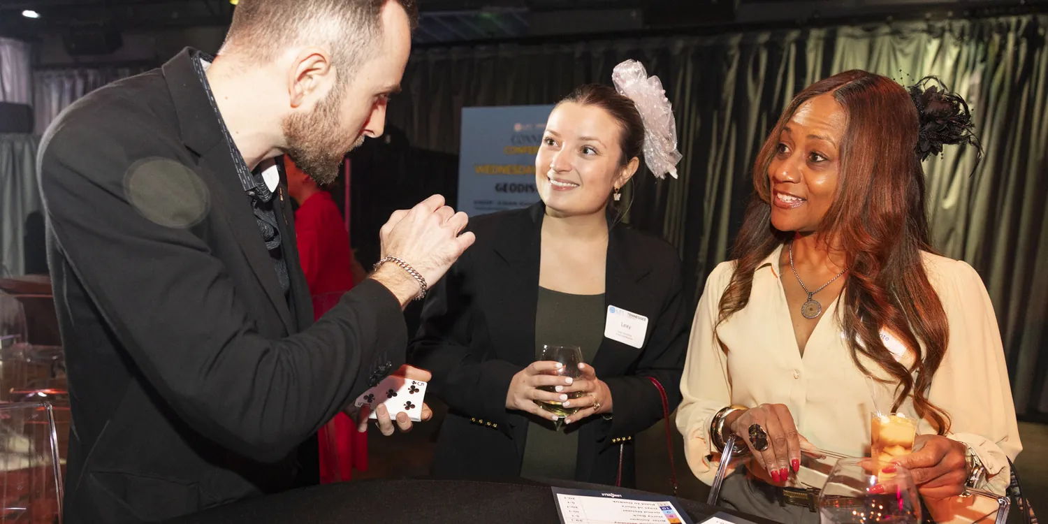 Frankie Foti performing close-up card magic for two guests at a corporate networking event