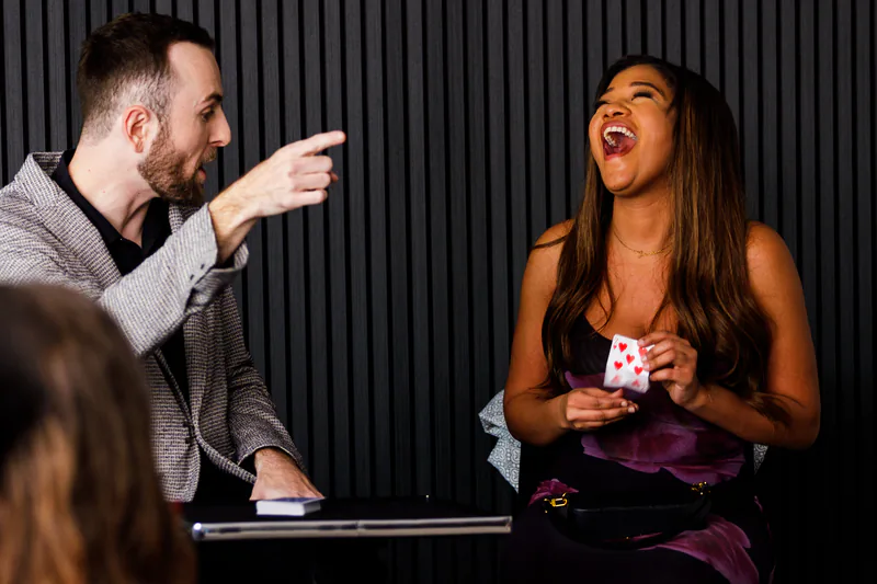 Frankie Foti performing close-up card magic for a guest holding a playing card at a private party